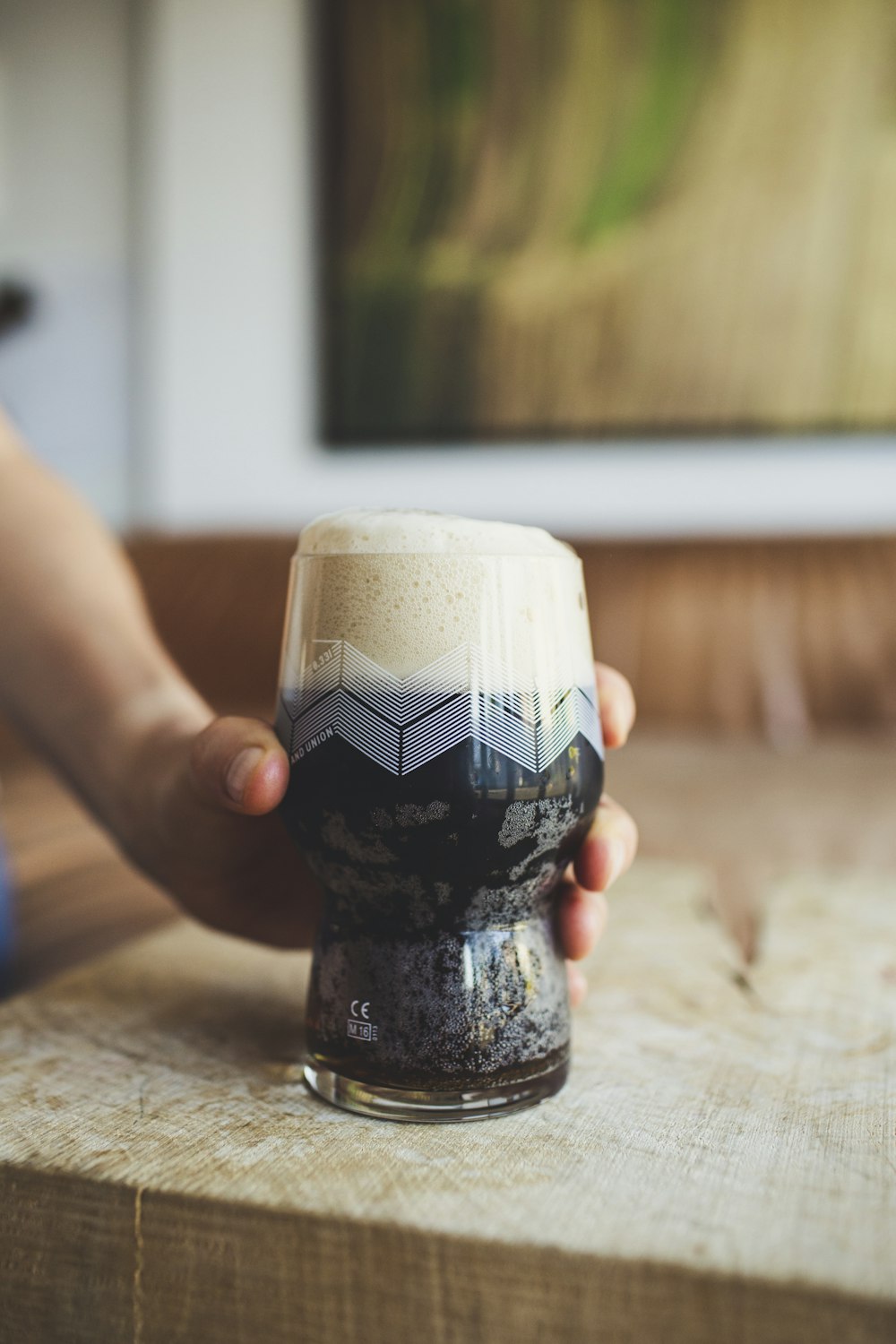 a person holding a glass of beer on a table