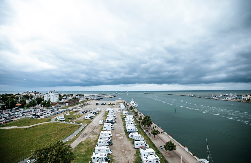 a parking lot next to a body of water under a cloudy sky