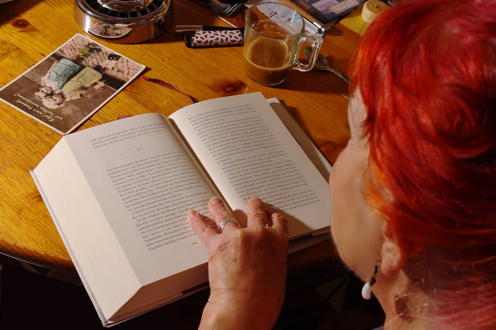 a woman sitting at a table reading a book