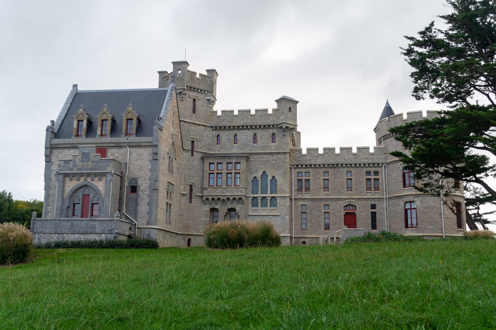 Un gran castillo como un edificio sentado en la cima de un exuberante campo verde