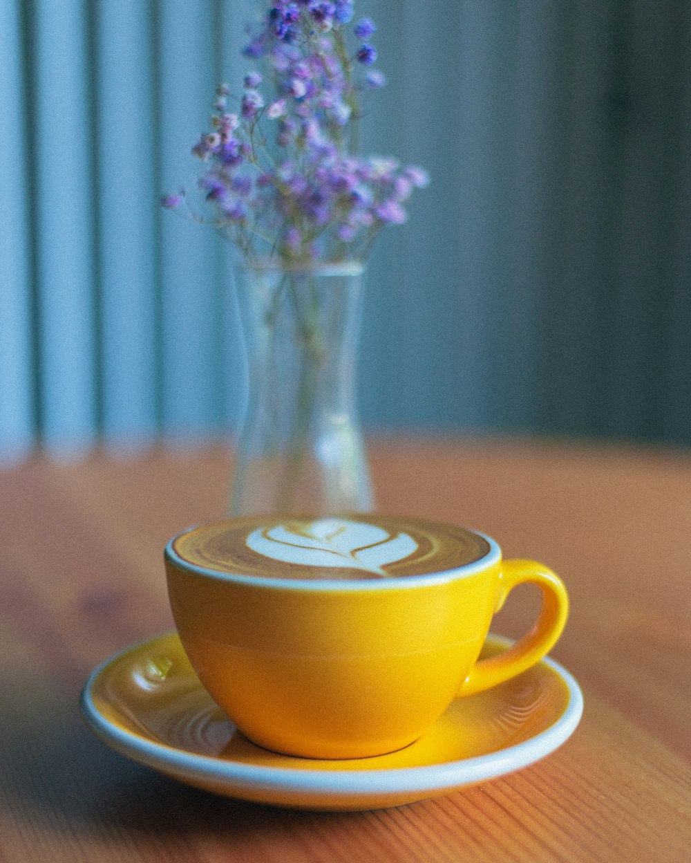 uma xícara de café e um vaso de flores sentado em uma mesa