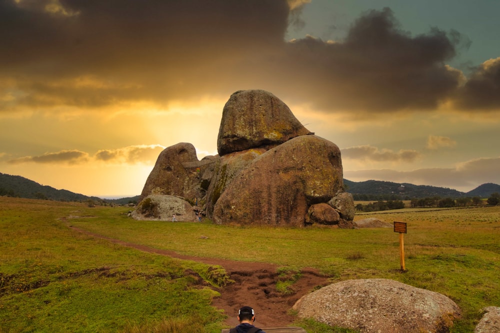 a person sitting on a bench in front of large rocks