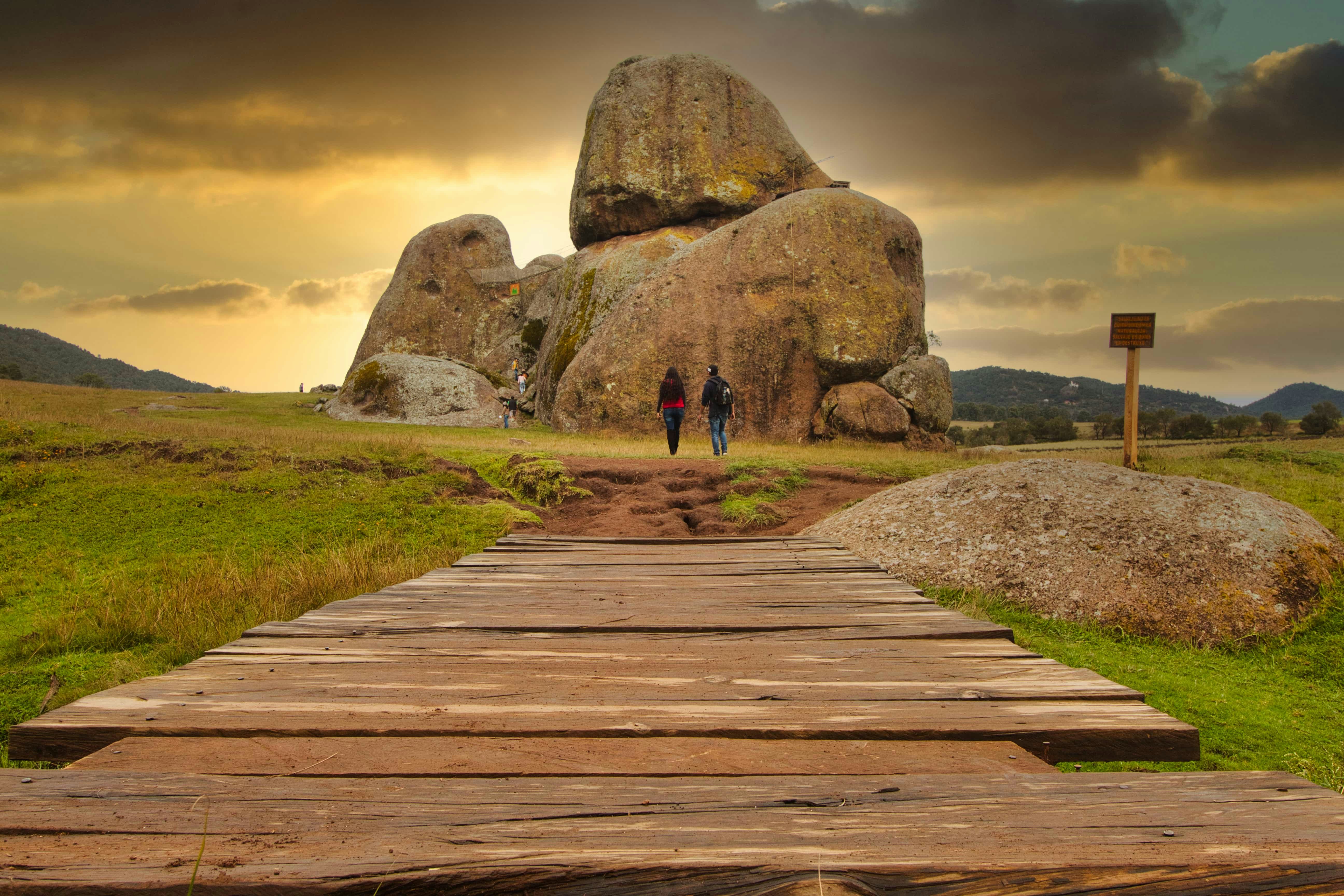 a wooden walkway leading to a large rock formation