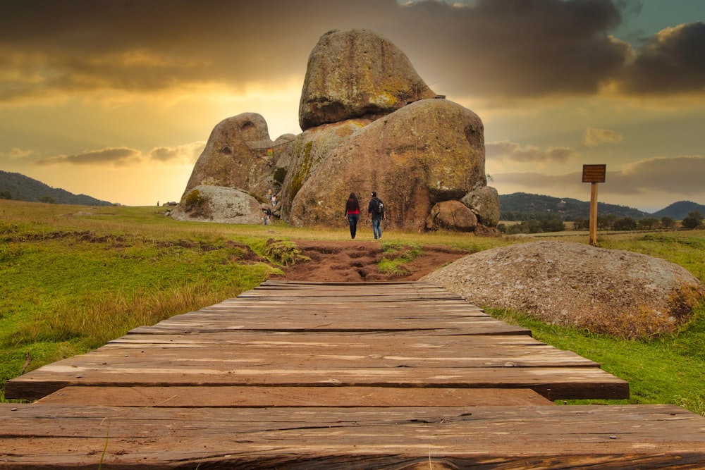 a wooden walkway leading to a large rock formation