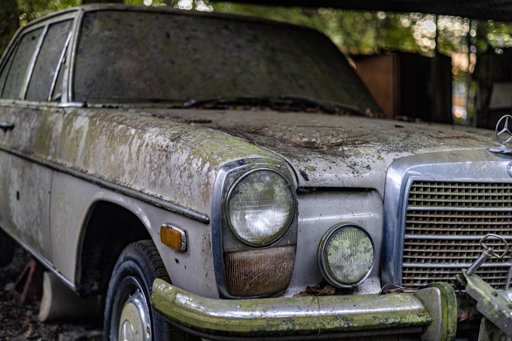 an old car is parked in the woods