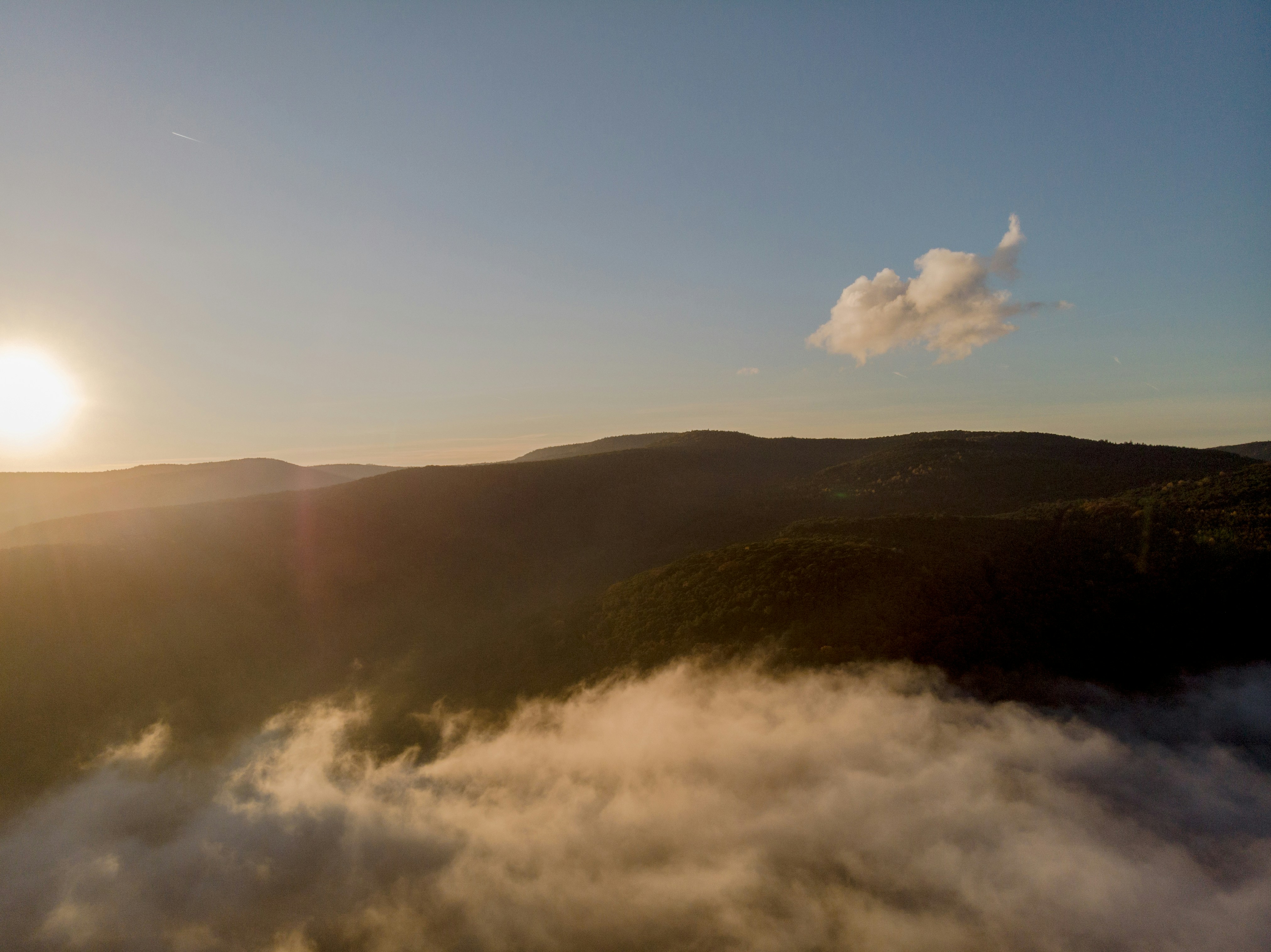 the sun is setting over the mountains and clouds