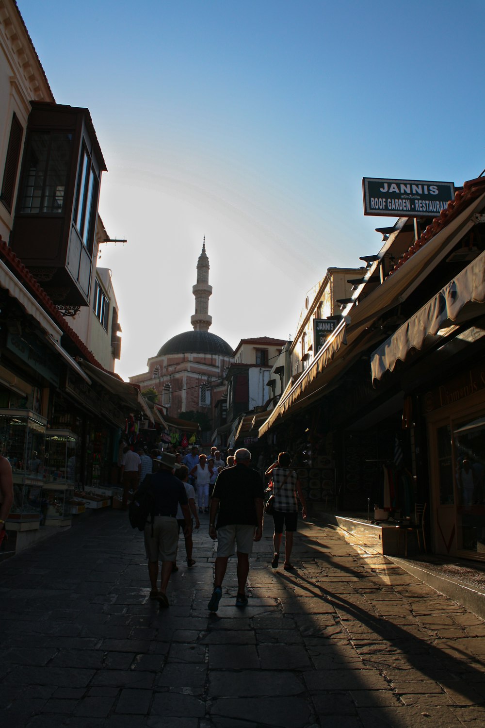 a group of people walking down a street next to tall buildings