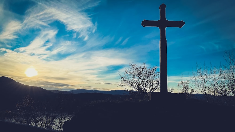 una croce sulla cima di una collina con uno sfondo del cielo