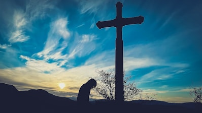 a person kneeling down in front of a cross