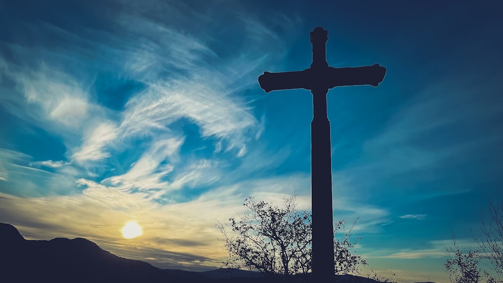 a cross on top of a hill with a sky background