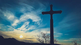 a cross on top of a hill with a sky background