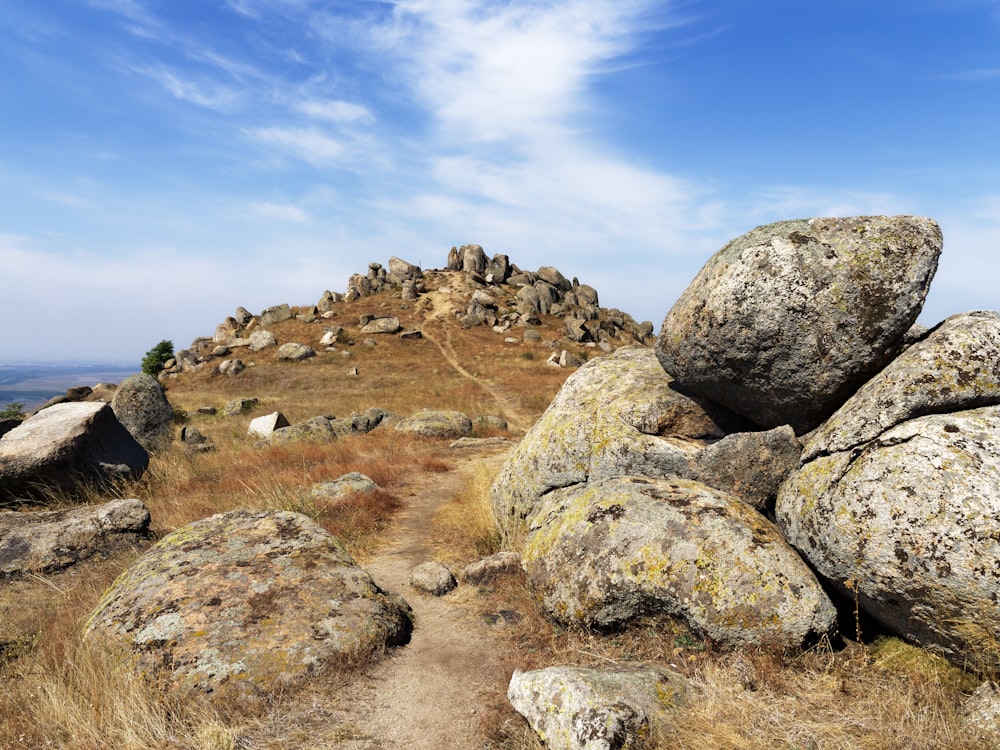 a rock formation on top of a grassy hill