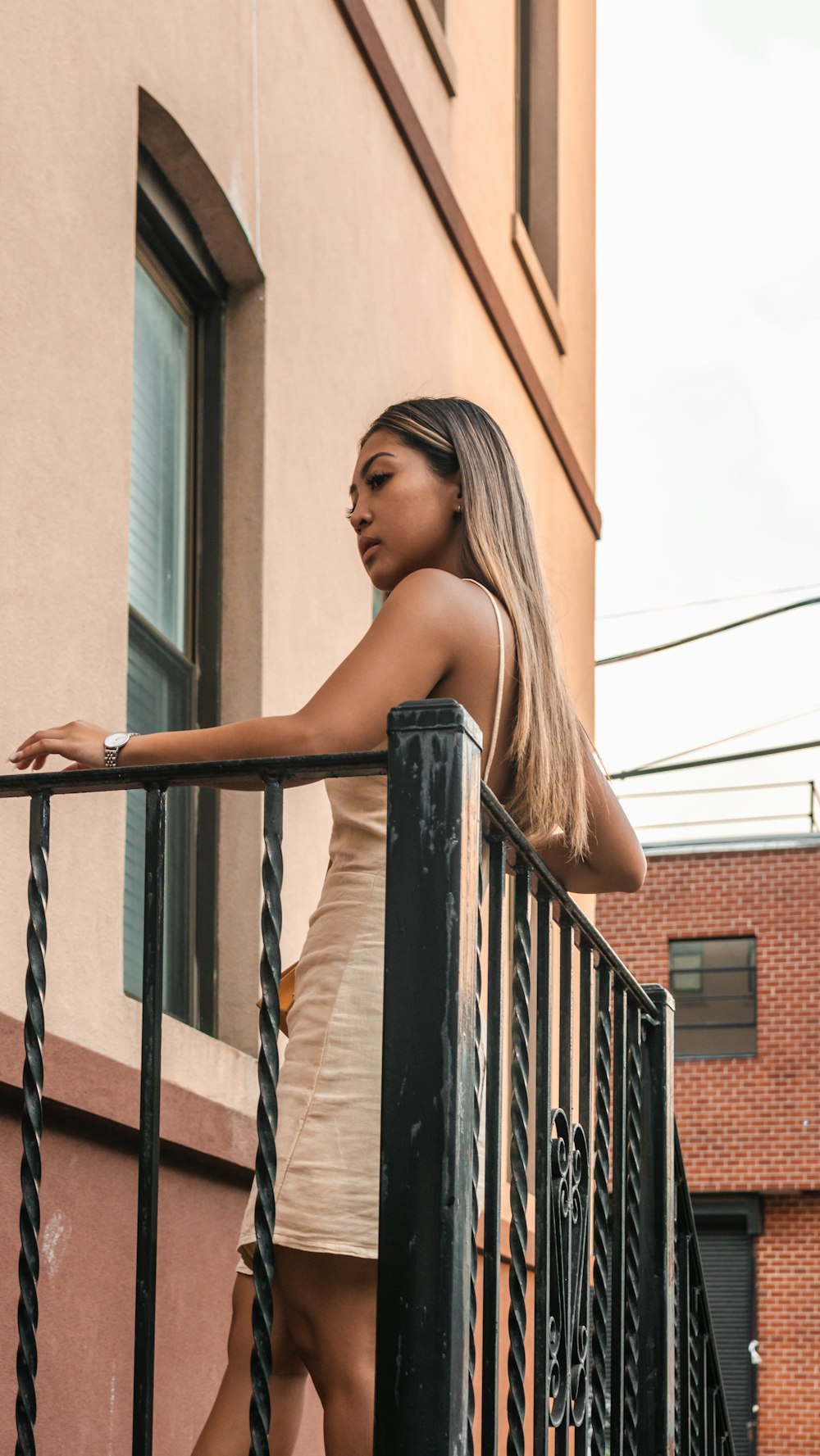 a woman standing on a balcony next to a building