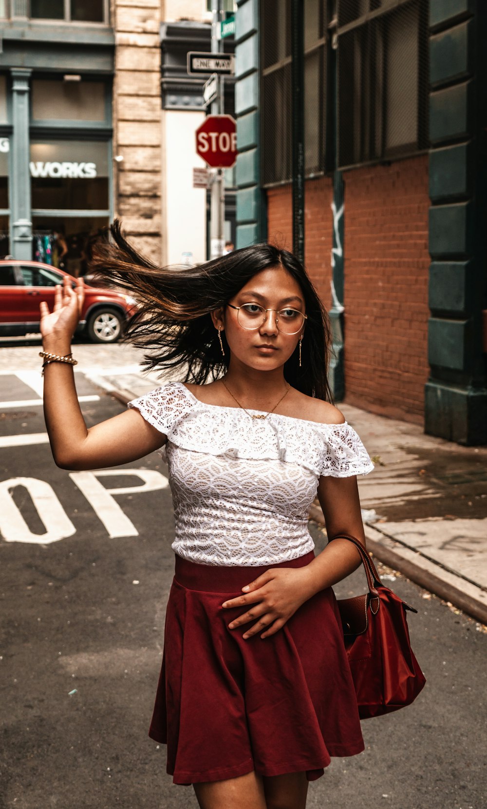 a woman walking down the street with her hair blowing in the wind