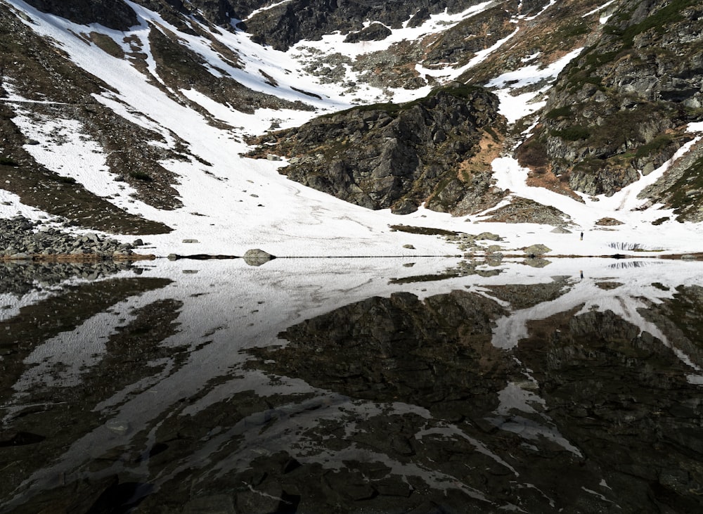 a snow covered mountain with a lake in the foreground