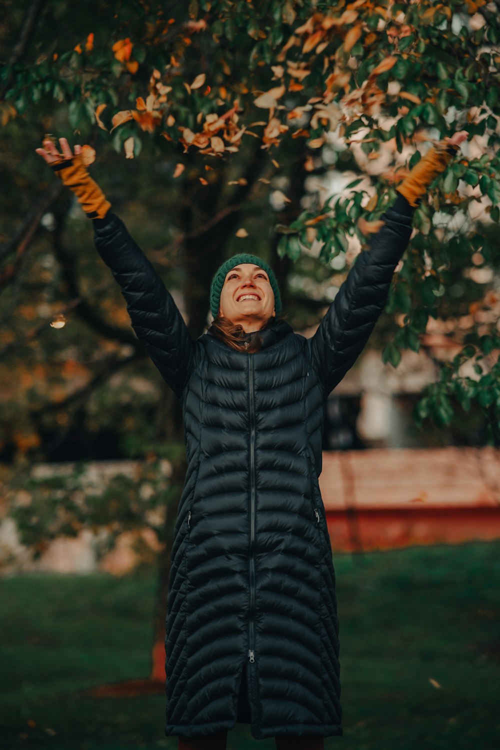 a woman standing under a tree with her hands in the air