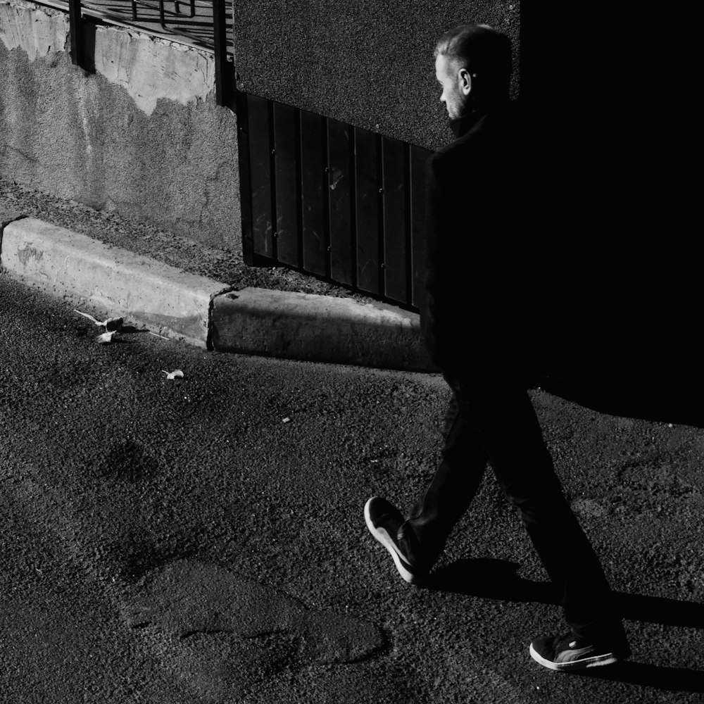 a black and white photo of a man walking down the street
