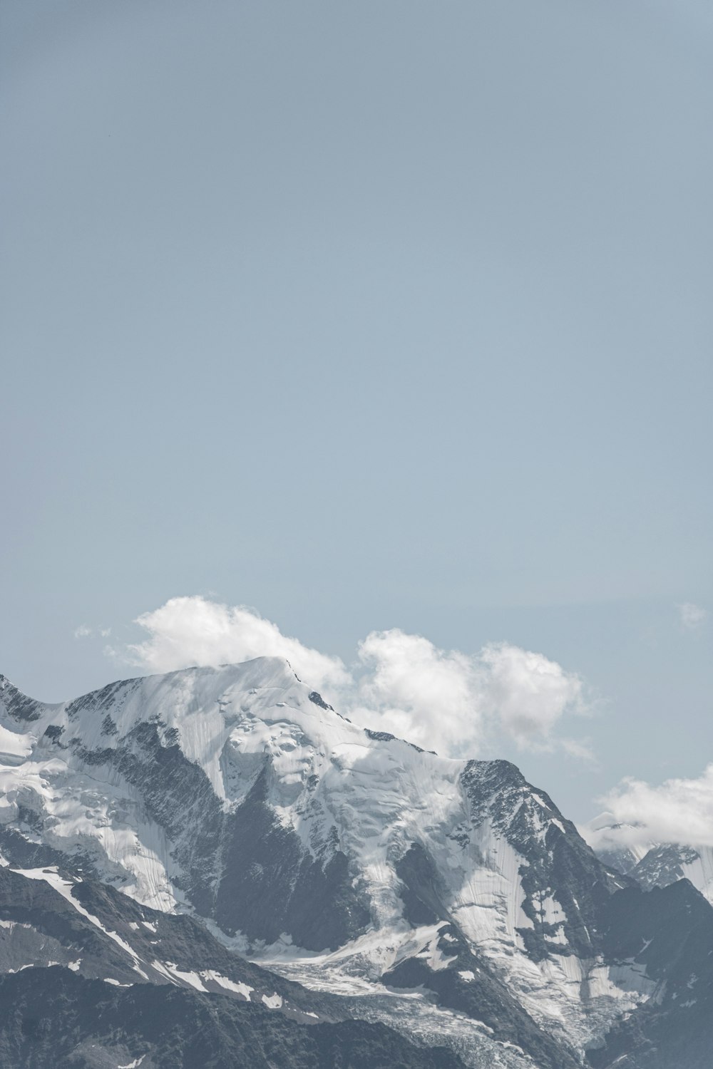 a snow covered mountain with a few clouds in the sky