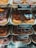 An assortment of donuts is displayed in trays behind a glass counter at a bakery. The variety includes chocolate iced glazed donuts with colorful sprinkles and plain glazed donuts. Each tray has a label indicating the type of donut and its price along with the calorie count.