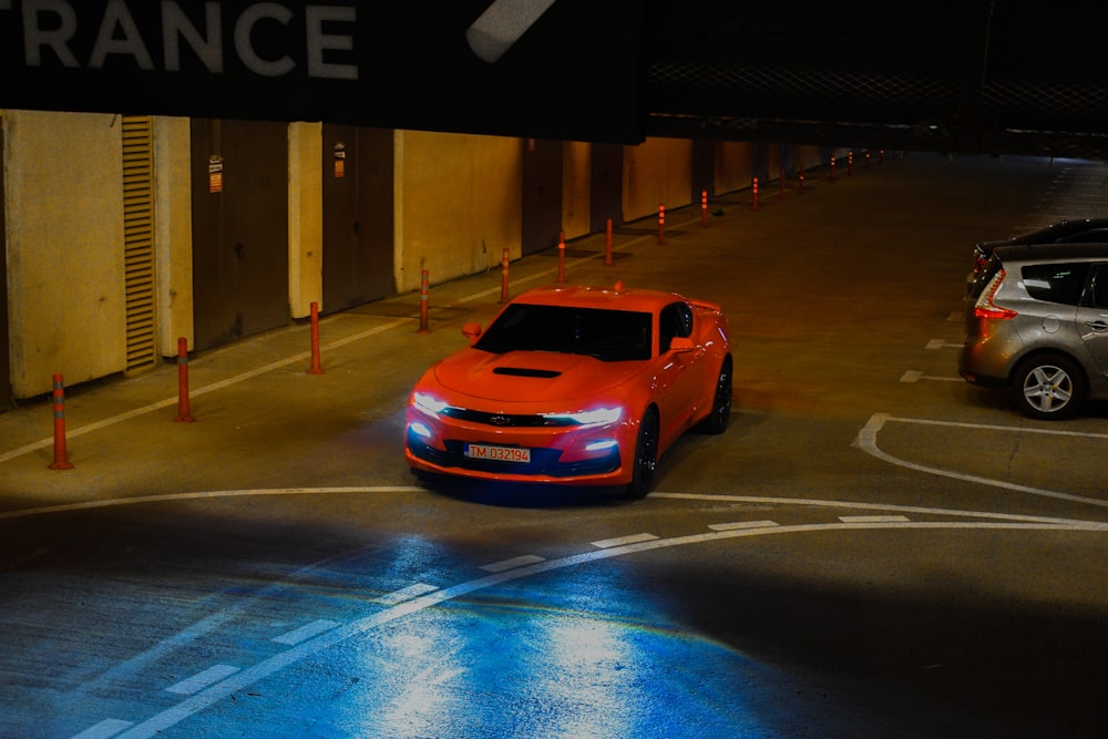 a red car driving down a street at night