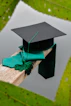 a graduation cap and a green tassel on a piece of wood