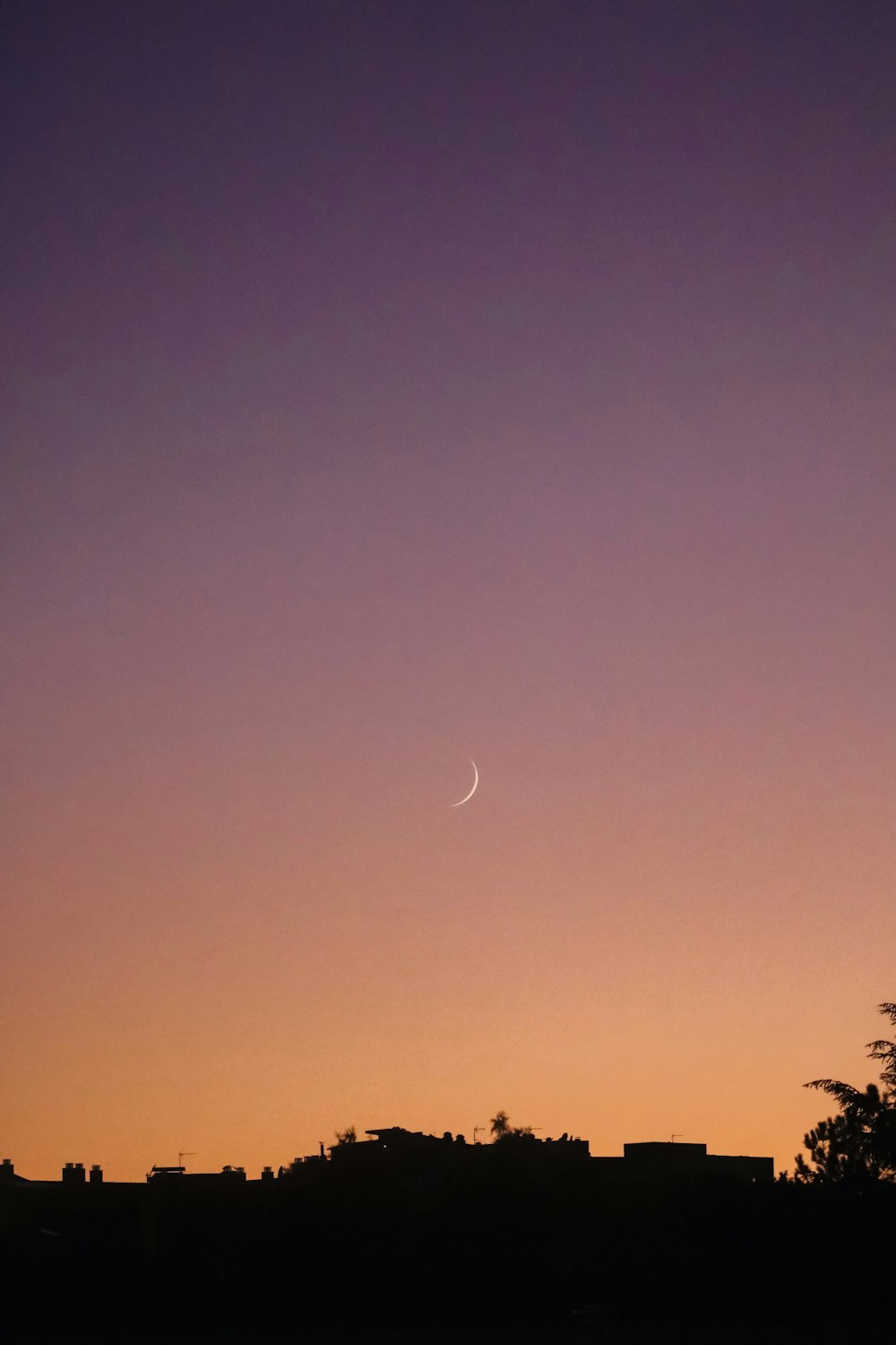 the moon is setting in the sky over a city