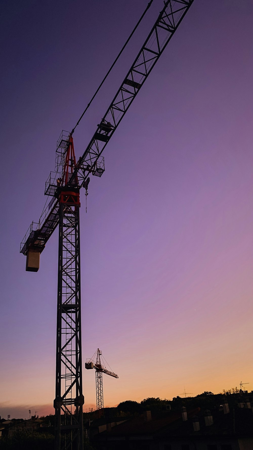 a crane is silhouetted against a purple sky