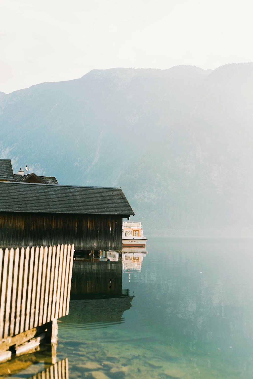 a boat house on a lake with mountains in the background