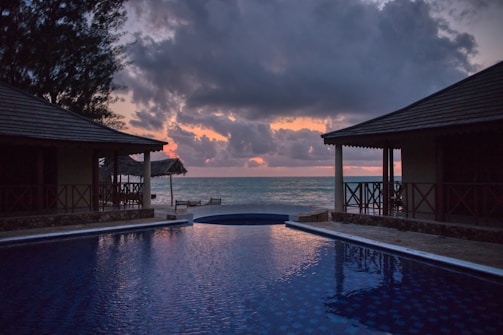 A serene beachfront villa with a private pool overlooking the turquoise ocean at sunset.