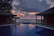 A serene beachfront villa at sunset with a private pool reflecting the warm colors of the sky.