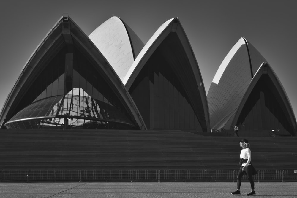 a man walking in front of the sydney opera house