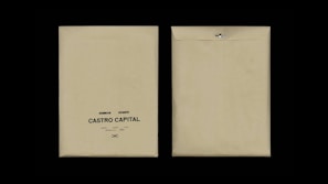 Two beige envelopes are displayed against a black background. The envelope on the left has printed text reading 'Desarrollo I, Rie, Auto Marketing, Castro Capital' with a decorative symbol below. The envelope on the right is flipped to show the plain back with a metal clasp.