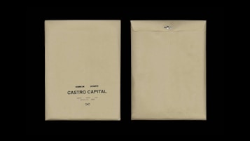 Two beige envelopes are displayed against a black background. The envelope on the left has printed text reading 'Desarrollo I, Rie, Auto Marketing, Castro Capital' with a decorative symbol below. The envelope on the right is flipped to show the plain back with a metal clasp.
