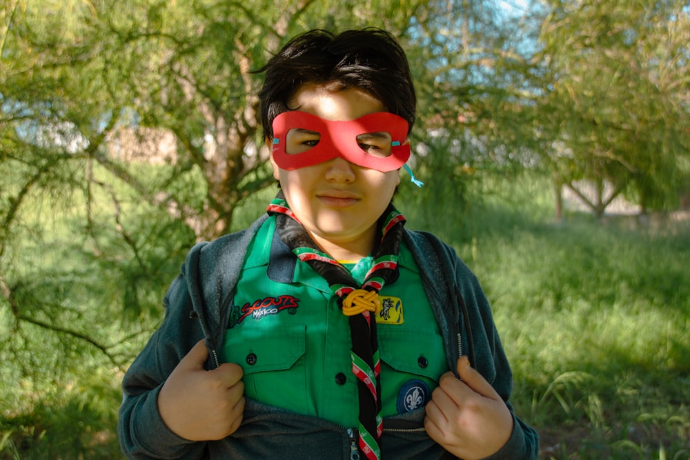 a young boy wearing a green shirt and a red mask