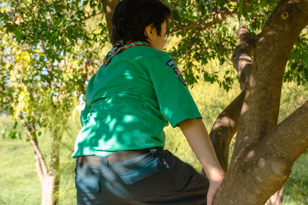 a man in a green shirt climbing up a tree