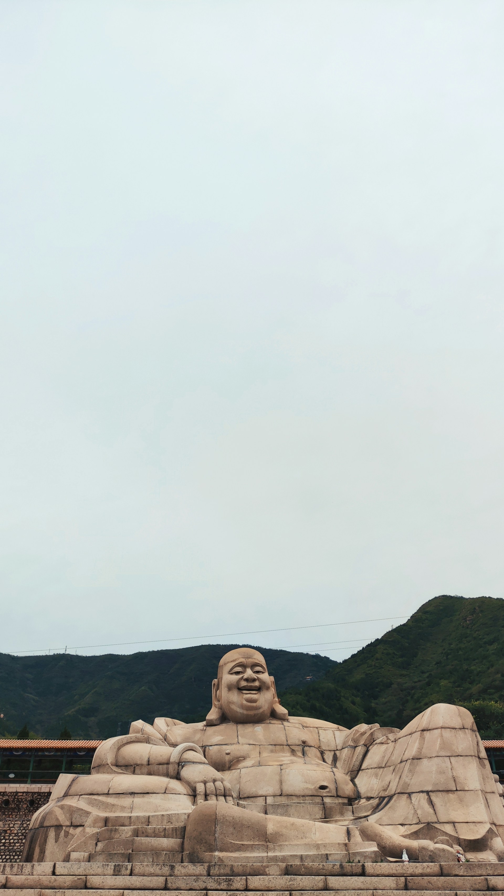 a large statue of a buddha sitting in front of a mountain