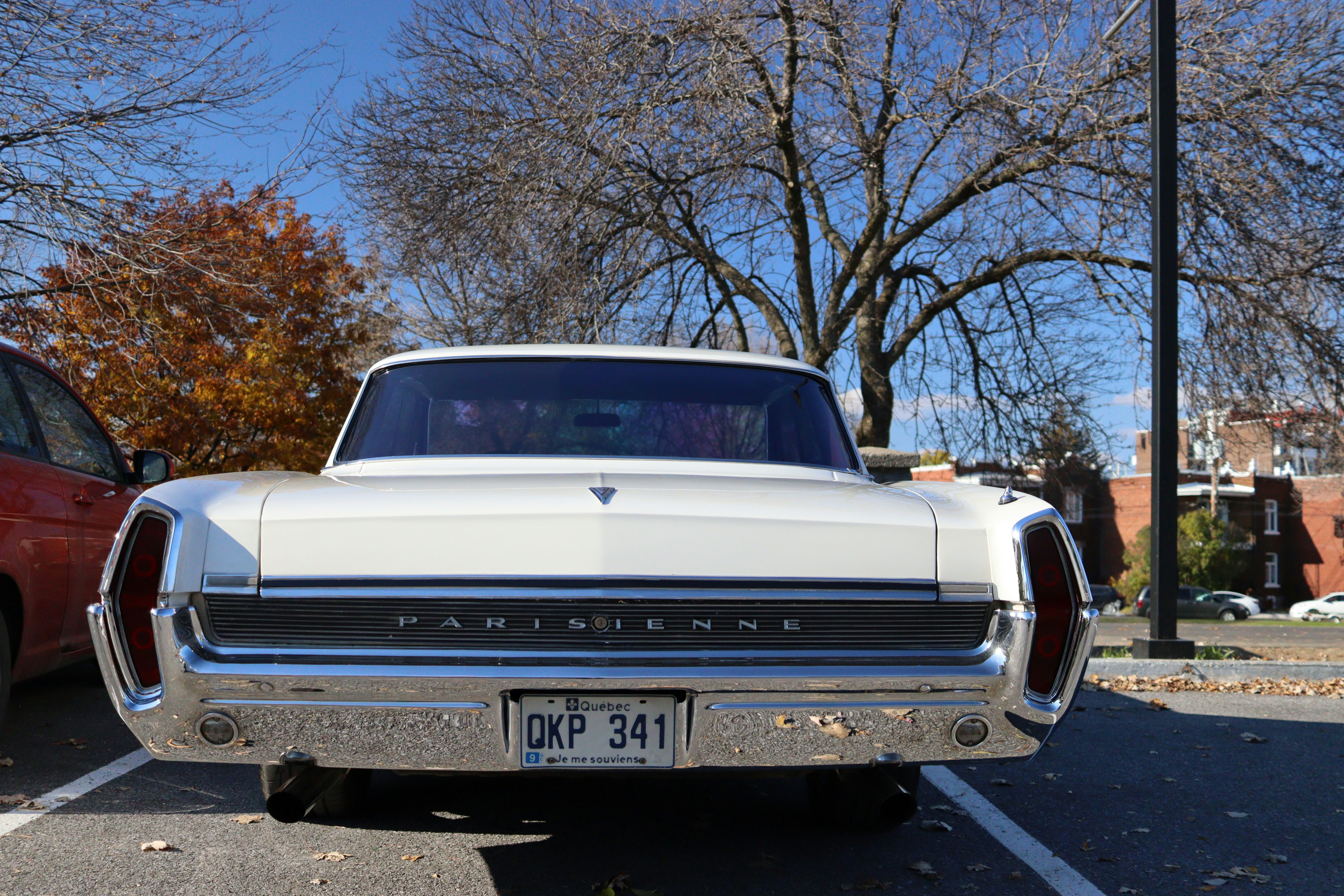 a white car parked in a parking lot next to a red car, Car Pontiac