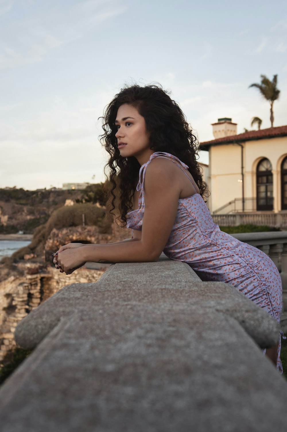 a woman sitting on a ledge next to a body of water