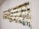 A collection of fishing lures is neatly organized on a white wall display board. The lures vary in color, size, and style, featuring a range of metallic hues and intricate designs. Each lure is equipped with hooks and displayed in an orderly manner.