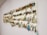 A collection of fishing lures is neatly organized on a white wall display board. The lures vary in color, size, and style, featuring a range of metallic hues and intricate designs. Each lure is equipped with hooks and displayed in an orderly manner.