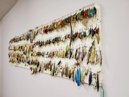 Array of colorful 3D printed fishing lures displayed on rustic wooden board.