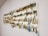 A collection of fishing lures is neatly organized on a white wall display board. The lures vary in color, size, and style, featuring a range of metallic hues and intricate designs. Each lure is equipped with hooks and displayed in an orderly manner.