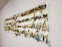 A collection of fishing lures is neatly organized on a white wall display board. The lures vary in color, size, and style, featuring a range of metallic hues and intricate designs. Each lure is equipped with hooks and displayed in an orderly manner.