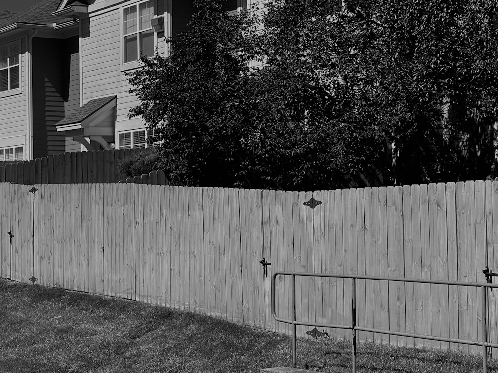 a black and white photo of a fence and a house