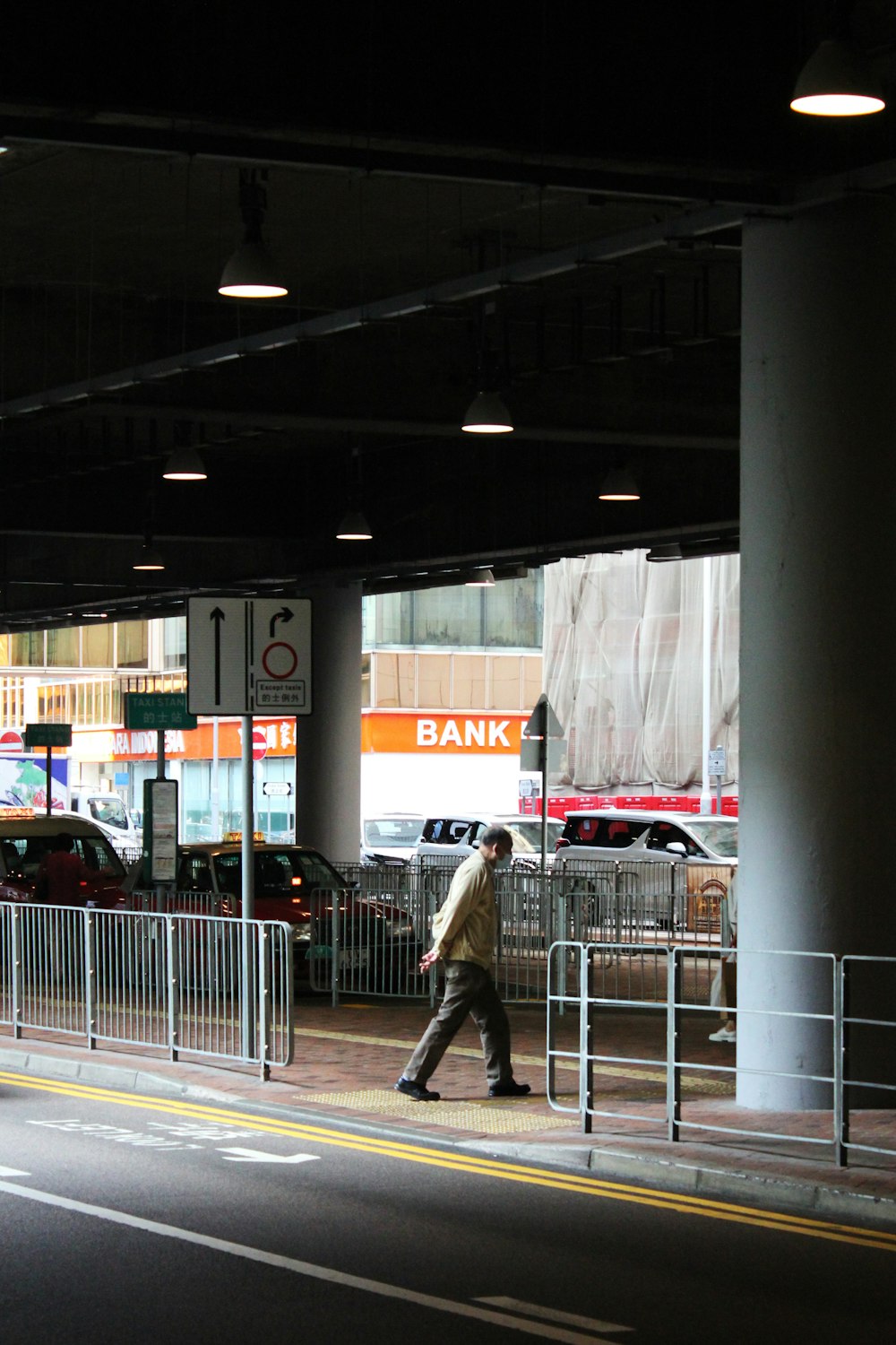 a man walking down a street next to a parking garage