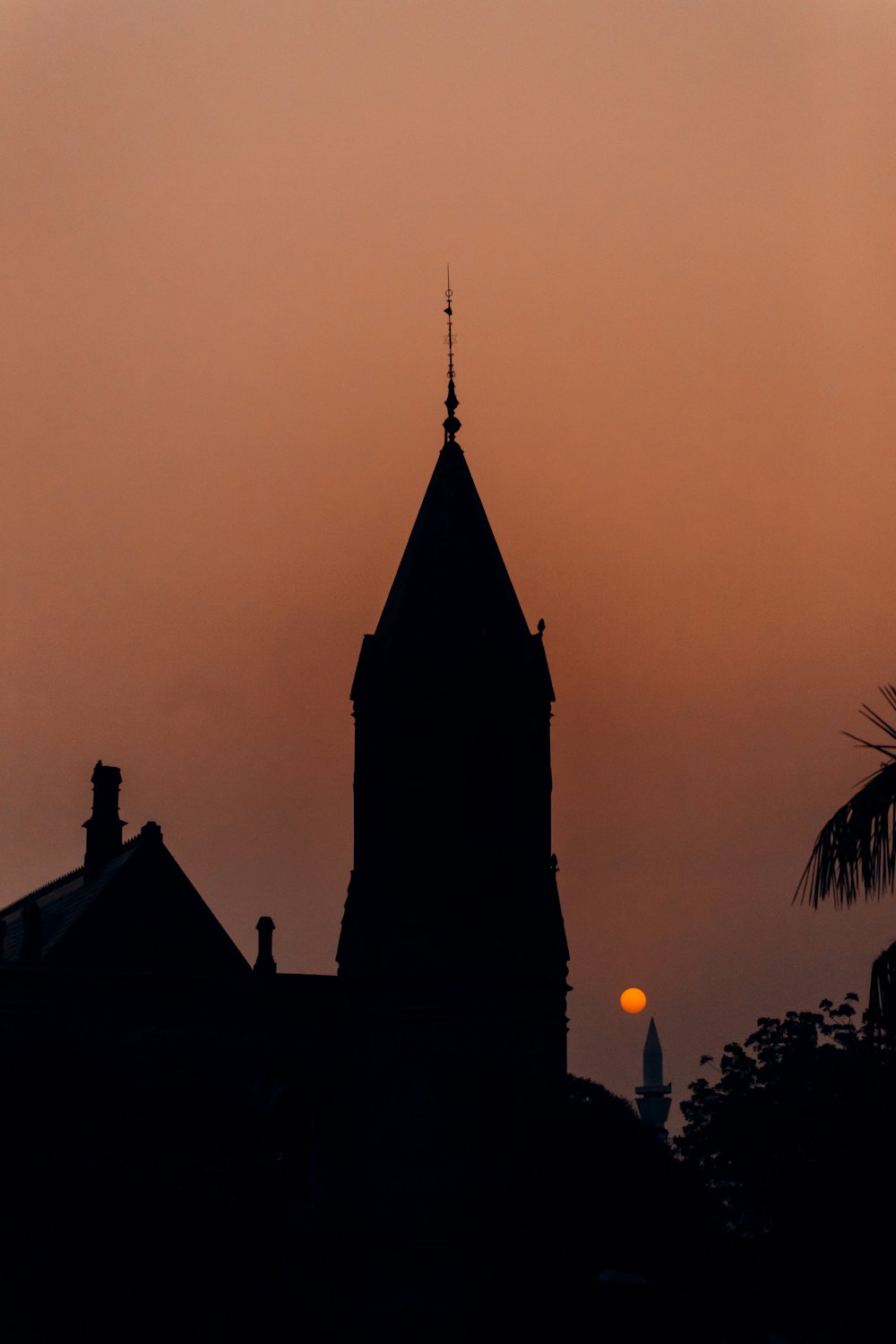the sun is setting behind a church steeple