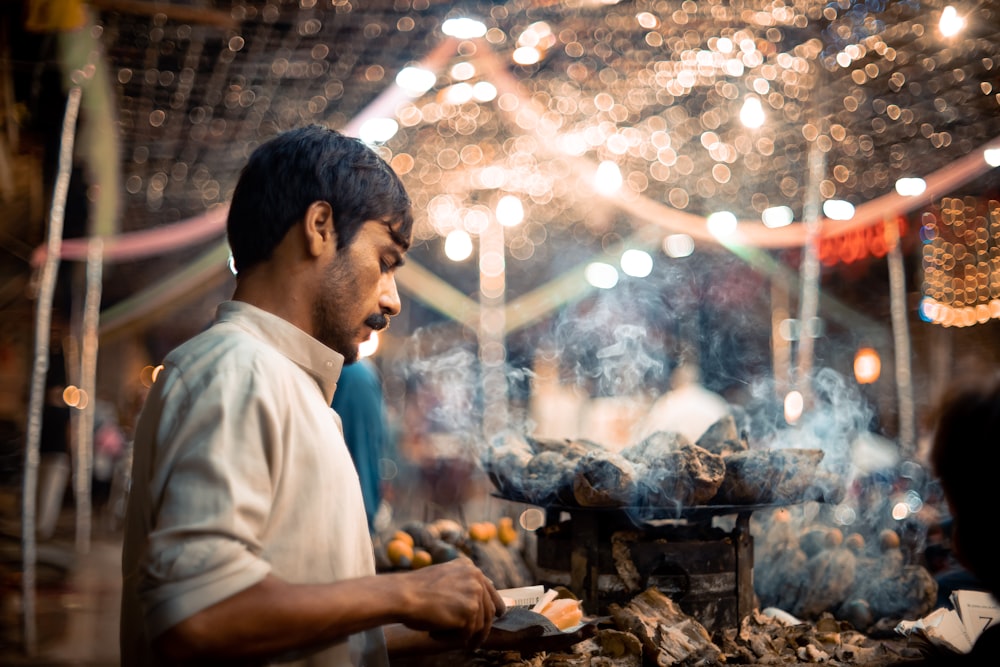 a man cooking food on a grill in a market