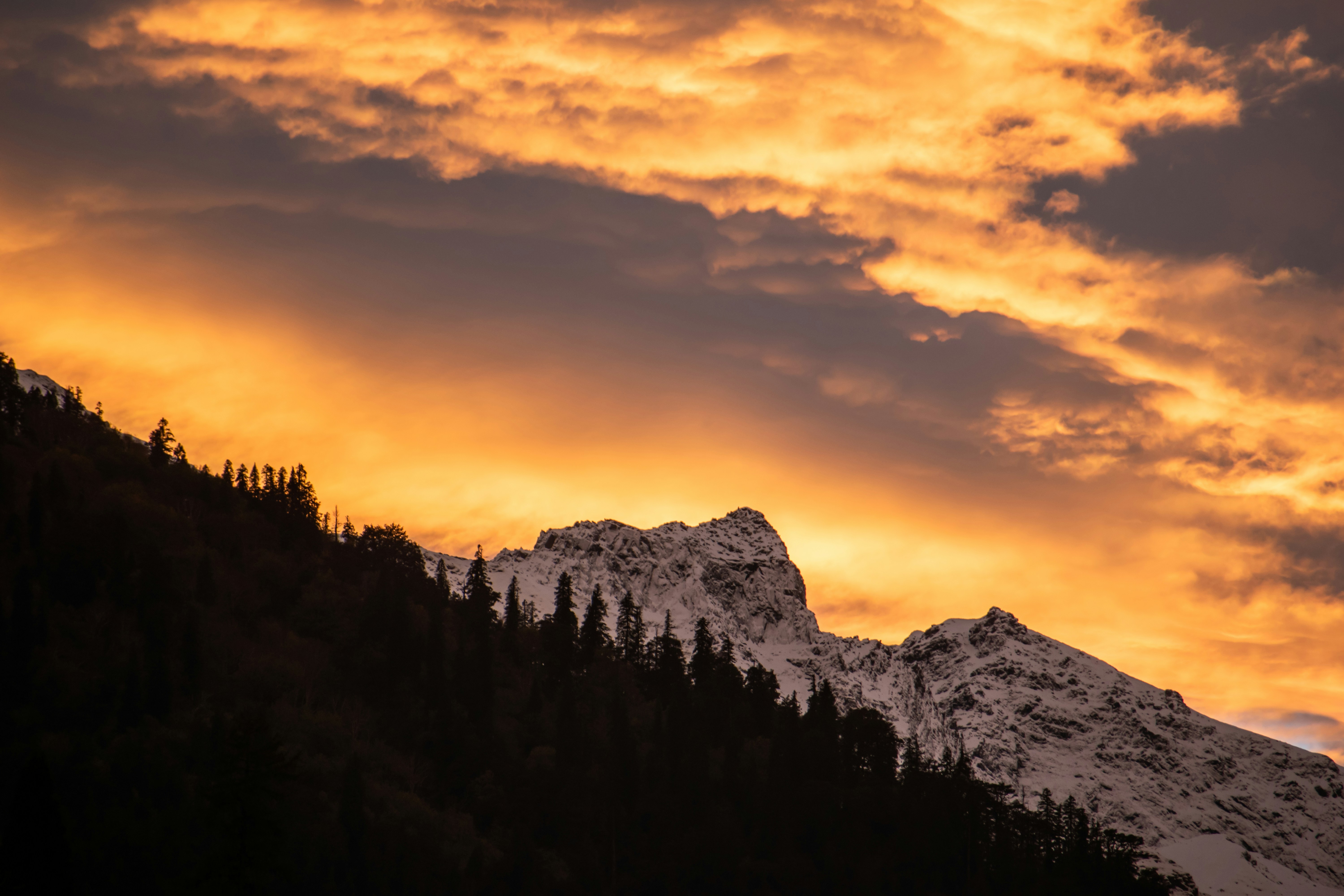 a mountain covered in snow under a cloudy sky
