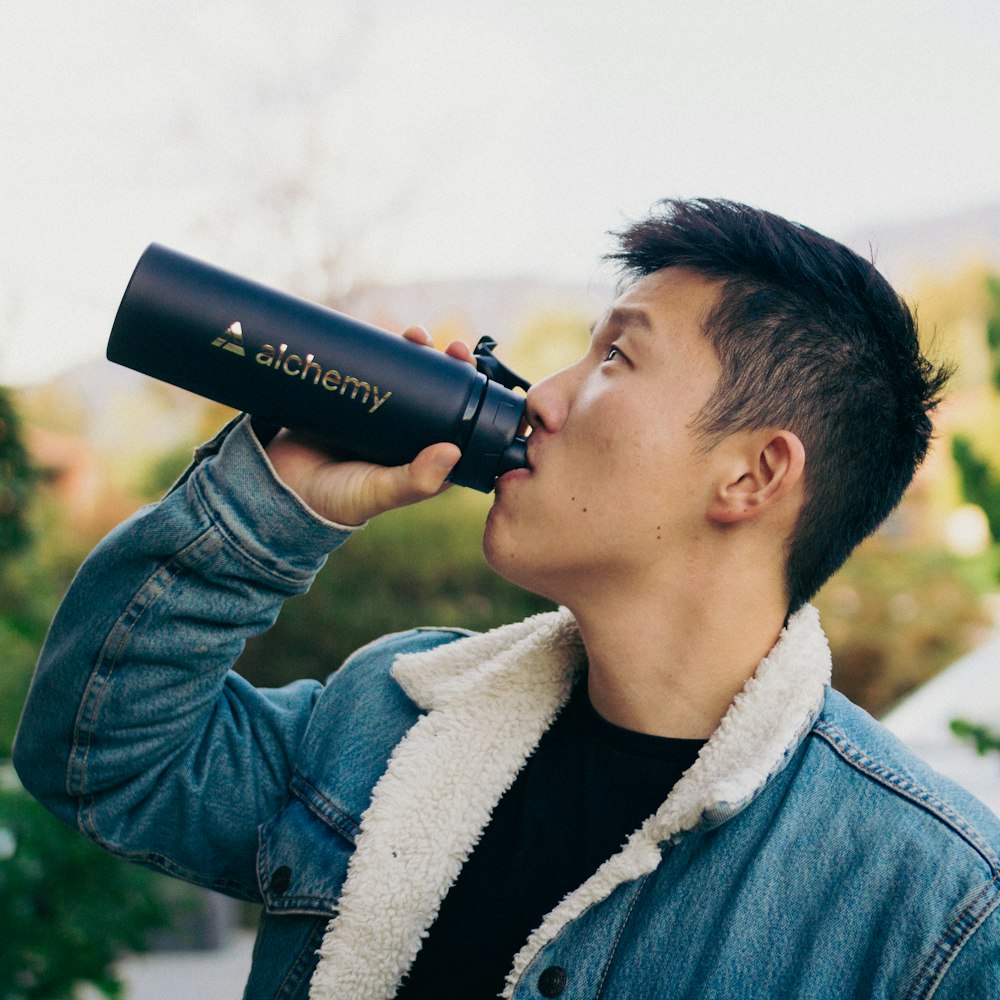 a man drinking out of a black cup