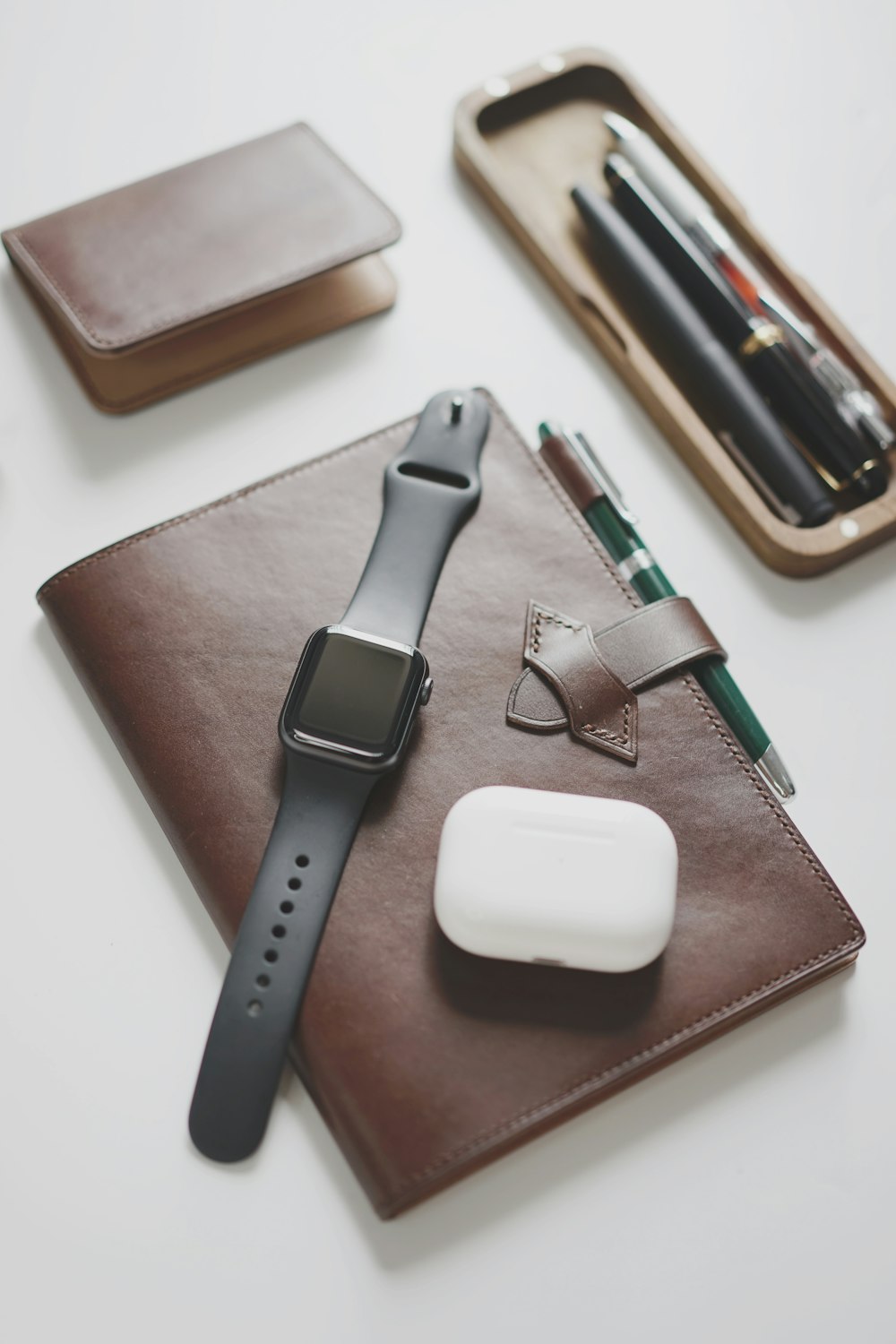 an apple watch, pen, and wallet on a table